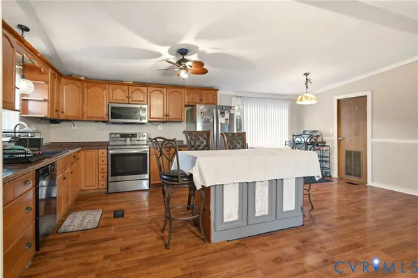a kitchen with stainless steel appliances kitchen island granite countertop a refrigerator a stove top oven a sink dishwasher and white cabinets with wooden floor