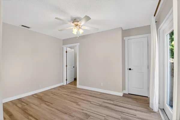 a view of an empty room with wooden floor and a window