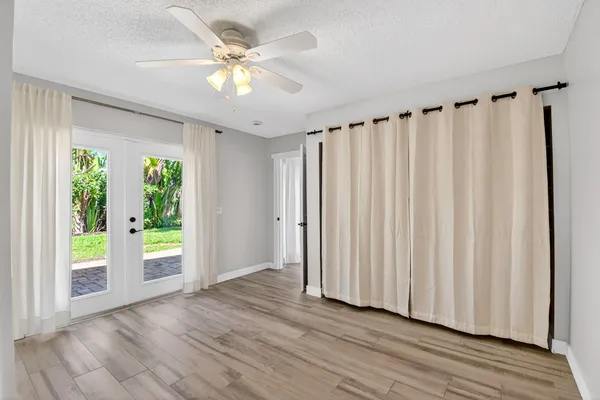 a view of an empty room with a window and wooden floor