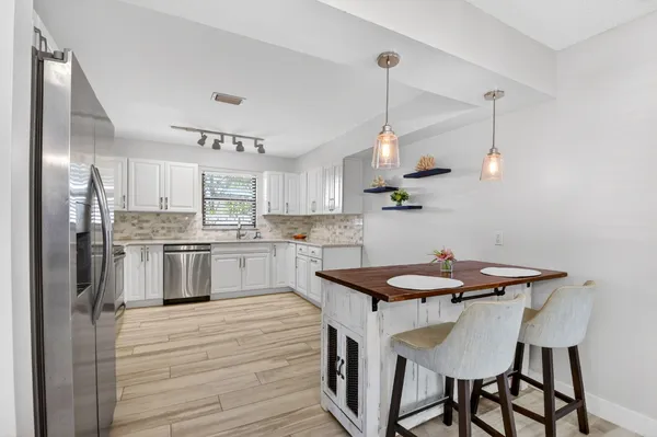 a kitchen with white cabinets stainless steel appliances and kitchen island