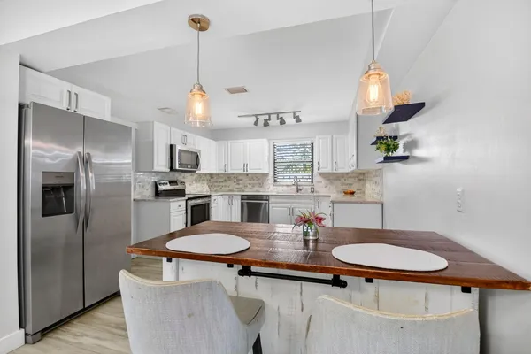 a kitchen with white cabinets stainless steel appliances and dining table