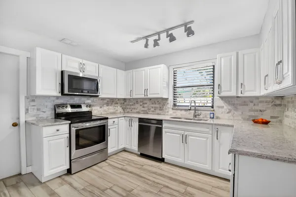 a kitchen with stainless steel appliances granite countertop a stove sink microwave and cabinets