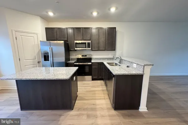 a kitchen with kitchen island stainless steel appliances a sink stove and refrigerator