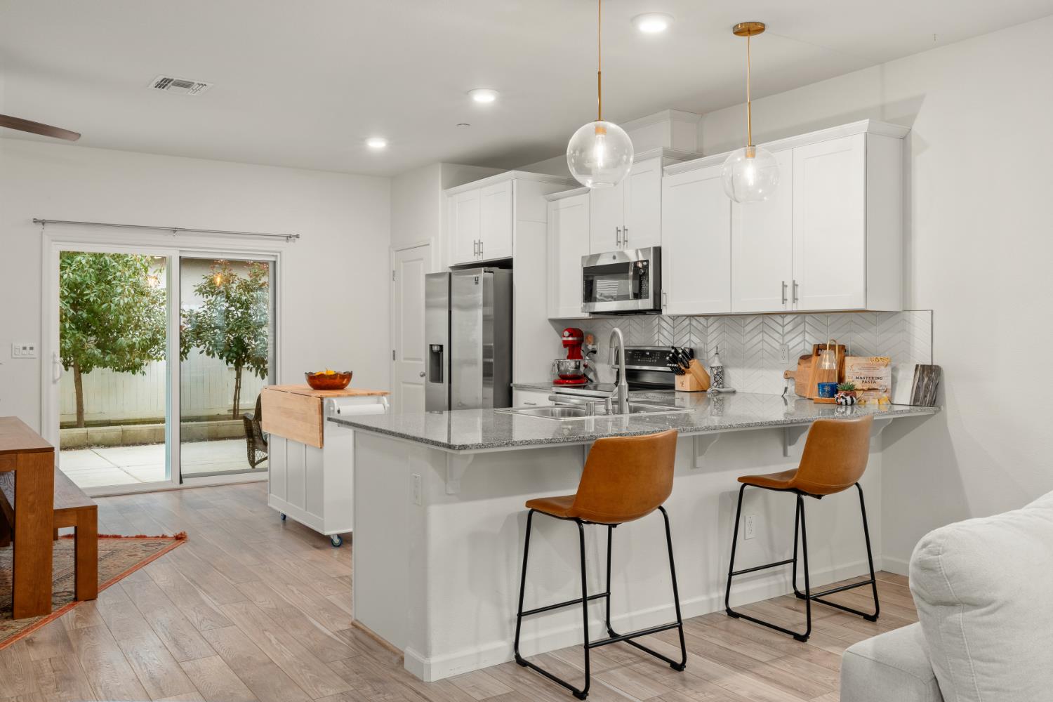 7457 Sobon Lane Rancho Murieta, CA 95683 - Photo 5 of 32 a kitchen with stainless steel appliances kitchen island granite countertop a refrigerator a stove top oven a sink dishwasher and white cabinets with wooden floor