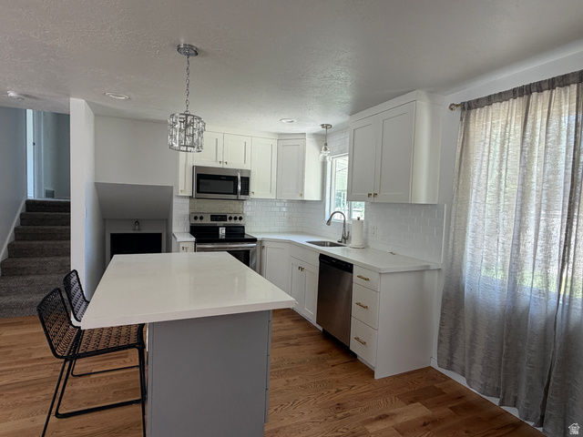 375 East 10560 South Sandy, UT 84070 - Photo 5 of 21 Modern kitchen featuring white cabinetry, stainless steel appliances, a white subway tile backsplash, and a central island with a light-toned countertop