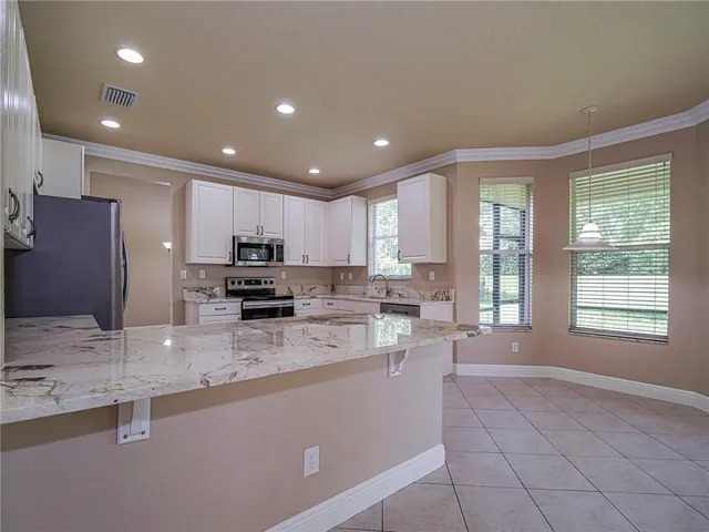 a large kitchen with granite countertop a stove a sink a window and dining table chair