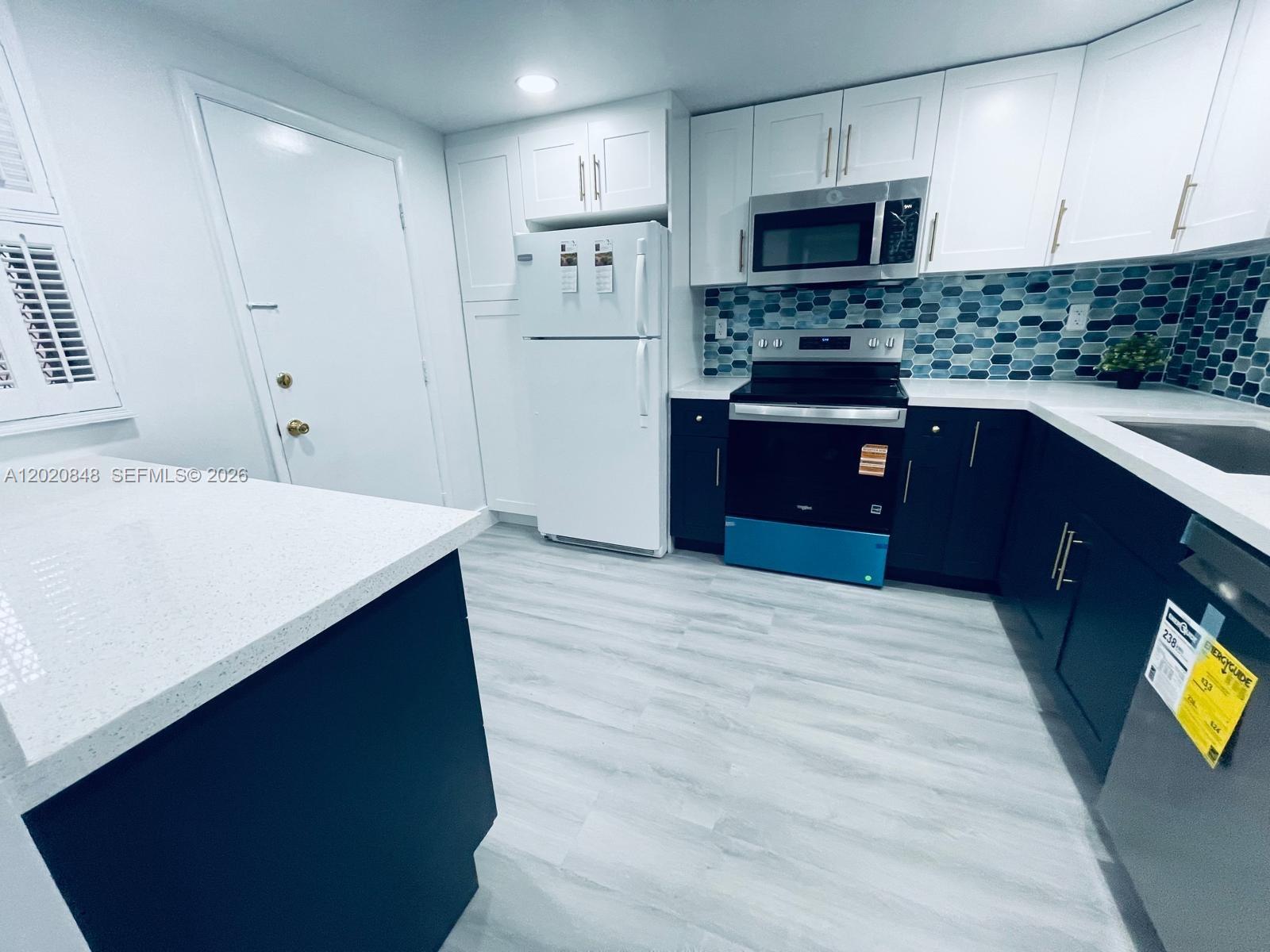 9175 Southwest 77th Avenue, Unit 306 Miami, FL 33156 - Photo 5 of 16 a kitchen with stainless steel appliances kitchen island granite countertop a refrigerator stove a sink and dishwasher