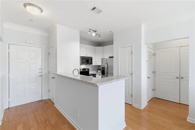 a kitchen with stainless steel appliances granite countertop white cabinets and a refrigerator