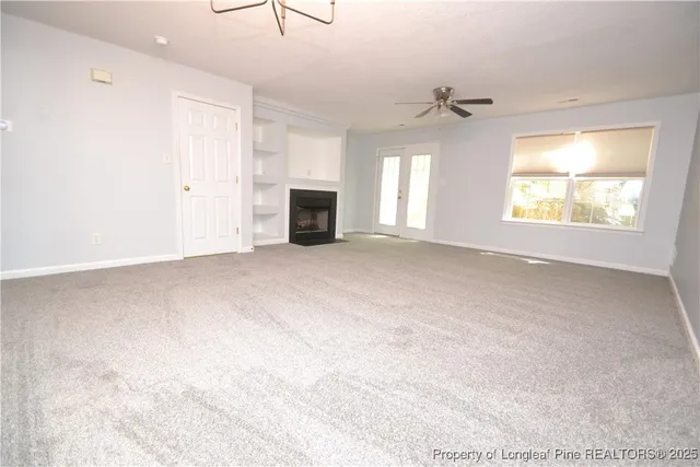 an empty room with windows fireplace and fans
