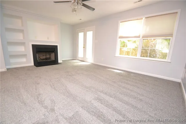an empty room with windows and fireplace