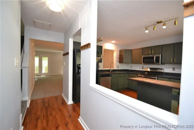 a kitchen with stainless steel appliances kitchen island granite countertop a refrigerator and a sink