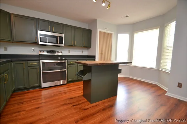 a kitchen with wooden floors appliances a sink cabinets and a window