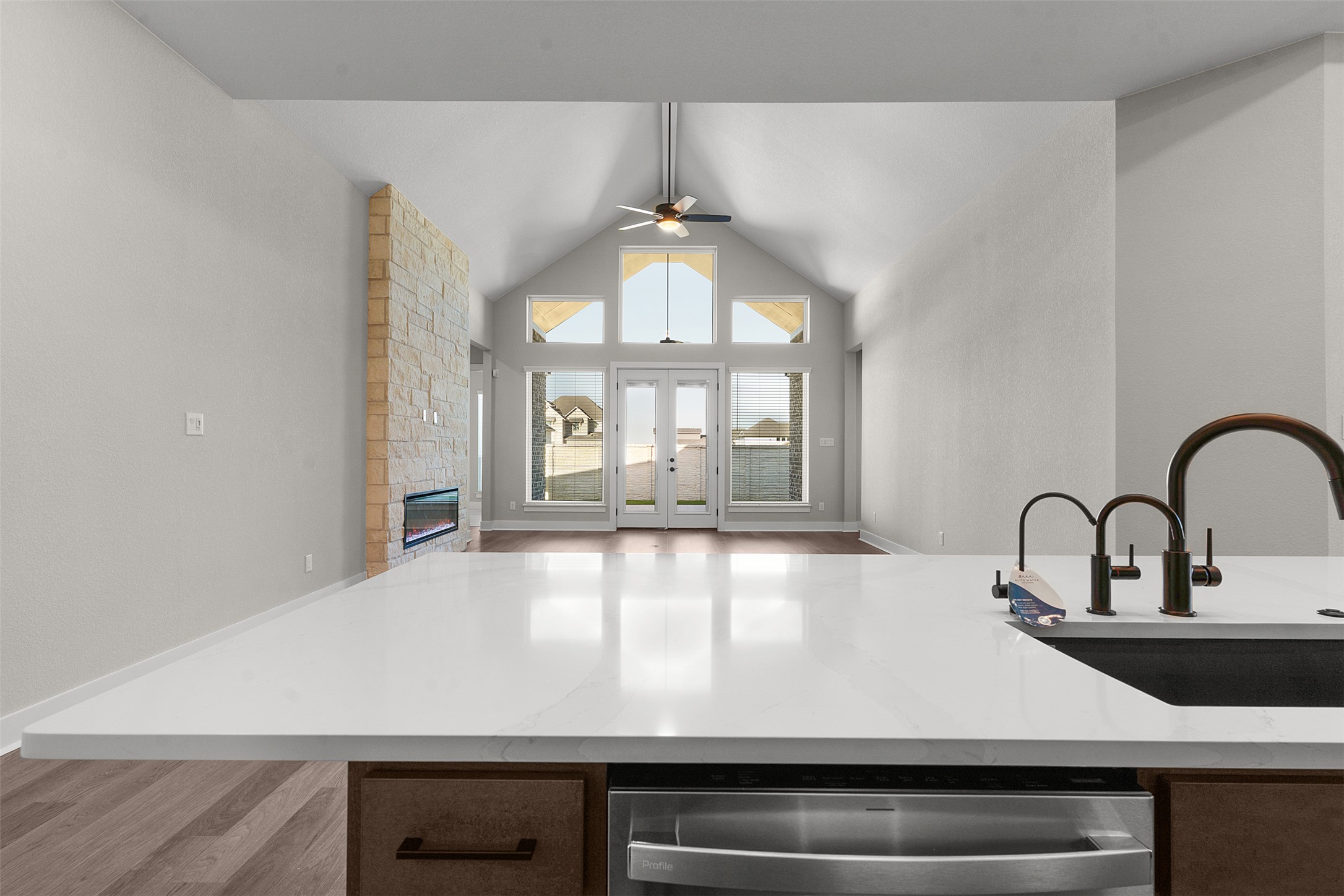 17216 Hope Bergman Road Pflugerville, TX 78660 - Photo 29 of 30 Kitchen featuring stainless steel dishwasher, open floor plan, a fireplace, light stone countertops, and light wood finished floors