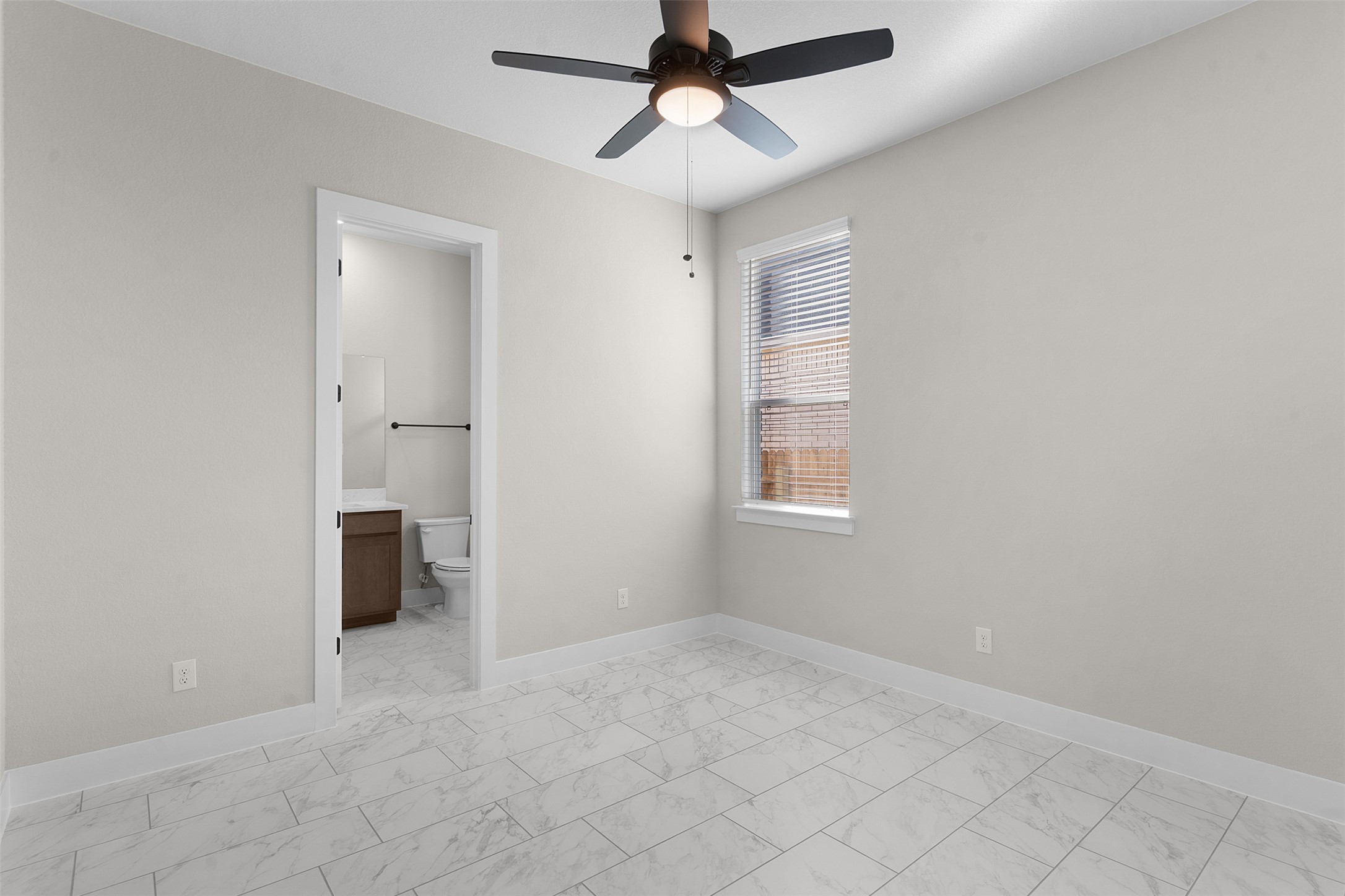 17216 Hope Bergman Road Pflugerville, TX 78660 - Photo 15 of 30 Unfurnished bedroom with a ceiling fan, ensuite bath, and light marble finish floors