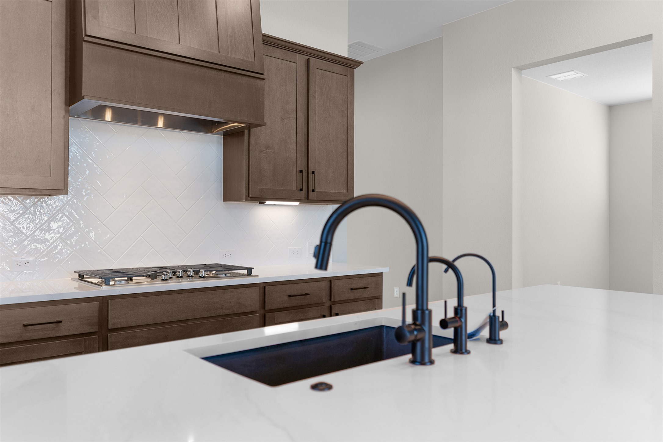 17216 Hope Bergman Road Pflugerville, TX 78660 - Photo 8 of 30 Kitchen with light stone countertops, premium range hood, stainless steel gas cooktop, and tasteful backsplash