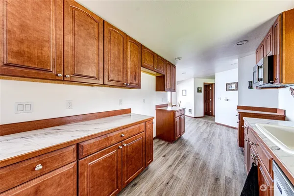 a kitchen with stainless steel appliances granite countertop a sink dishwasher stove and wooden cabinets with wooden floor