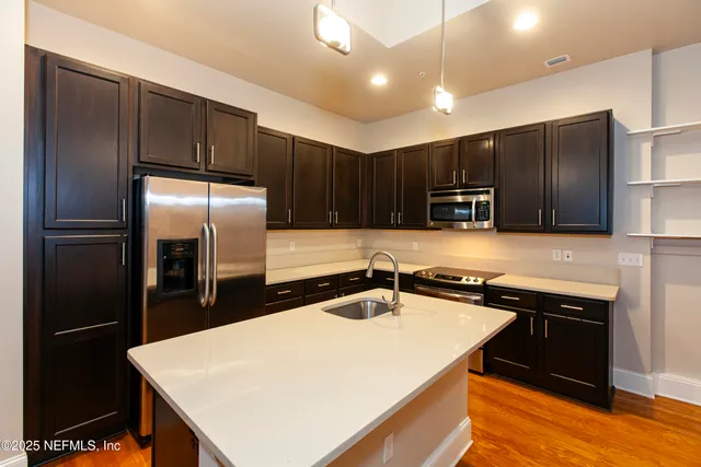 a kitchen with kitchen island a counter top space cabinets and stainless steel appliances