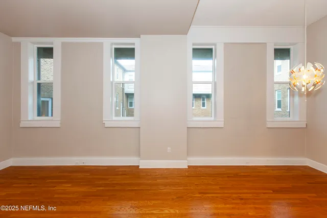 a view of an empty room with window and wooden floor