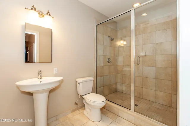 a bathroom with a shower sink mirror and toilet