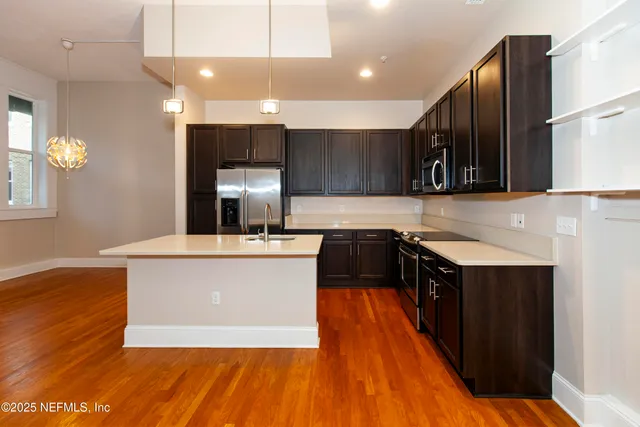 a kitchen with kitchen island a counter top space a sink a stove and wooden floor