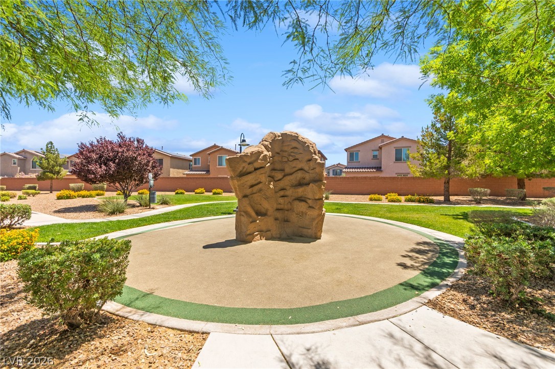 6435 Point Isabel Way Las Vegas, NV 89122 - Photo 52 of 57 A well-maintained community park features a climbing boulder, lush green spaces, and neatly manicured landscaping.