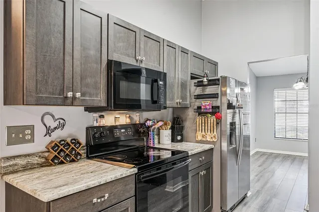 a kitchen with stainless steel appliances granite countertop a stove a sink dishwasher and a refrigerator with wooden floor