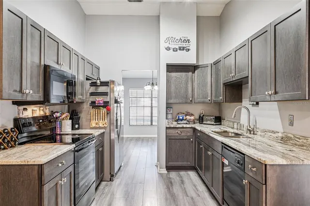 a kitchen with granite countertop a sink cabinets and stainless steel appliances