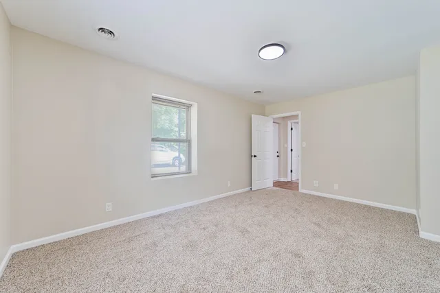 a view of an empty room with a window and bathroom