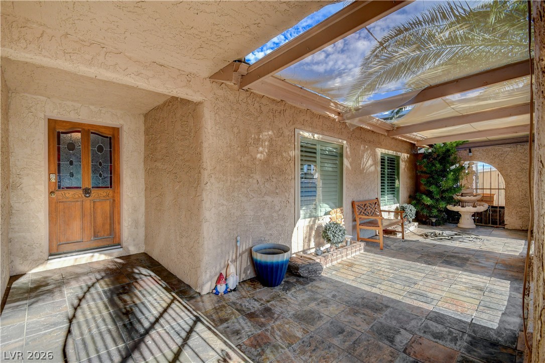 An inviting tiled courtyard features stucco walls and a partially covered overhead canopy.