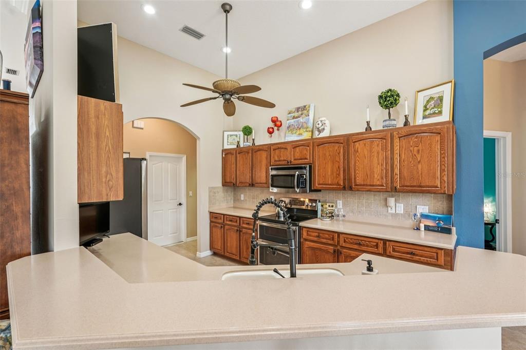 626 May Apple Way Venice, FL 34293 - Photo 13 of 60 a kitchen with stainless steel appliances kitchen island granite countertop a sink a stove and a refrigerator