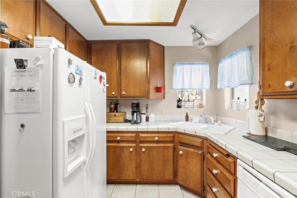14243 Wycliff Way Magalia, CA 95954 - Photo 52 of 65 a kitchen with a refrigerator a sink and dishwasher with wooden cabinets