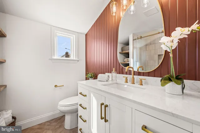 a bathroom with a granite countertop toilet sink and mirror
