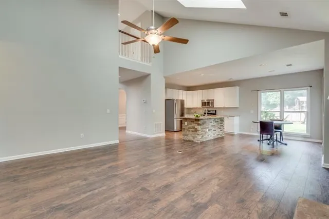 an empty room with chandelier fan and windows