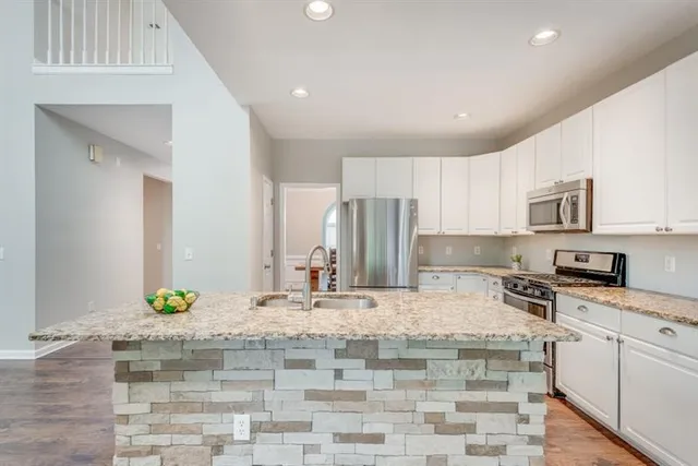 a kitchen with kitchen island granite countertop a sink stove and cabinets