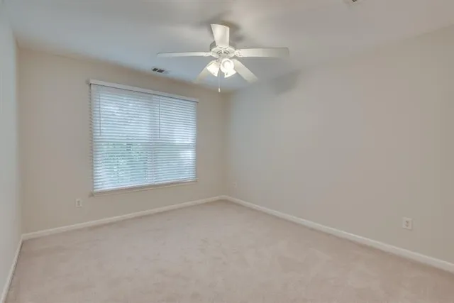 an empty room with a ceiling fan and a window
