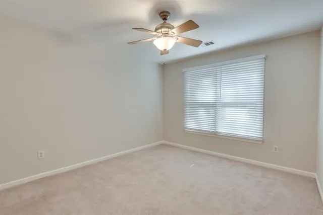 an empty room with a ceiling fan and a window