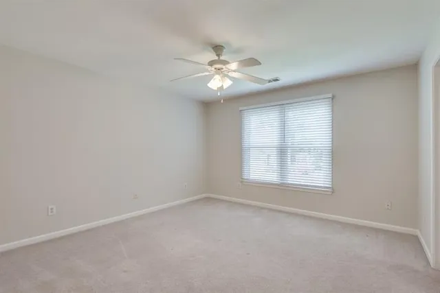 an empty room with a ceiling fan and a window