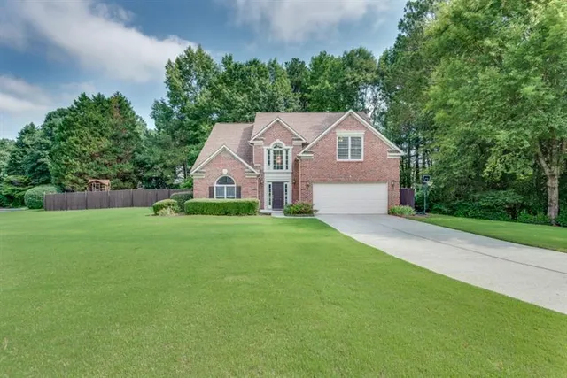 a front view of a house with a yard and trees
