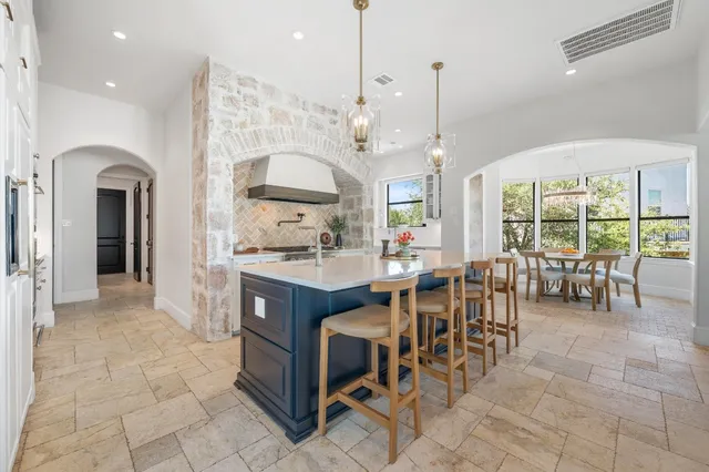 a kitchen with stainless steel appliances granite countertop table chairs and a view of living room