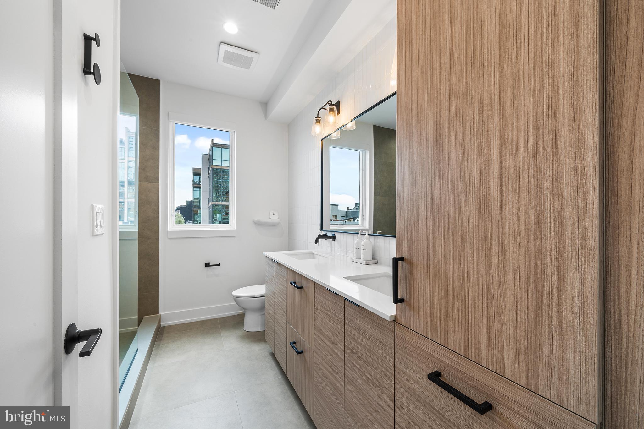 1322 Rodman Street Philadelphia, PA 19147 - Photo 22 of 38 a spacious bathroom with a double vanity sink a mirror and a toilet