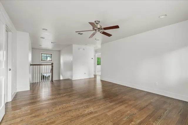 a view of empty room with wooden floor and ceiling fan
