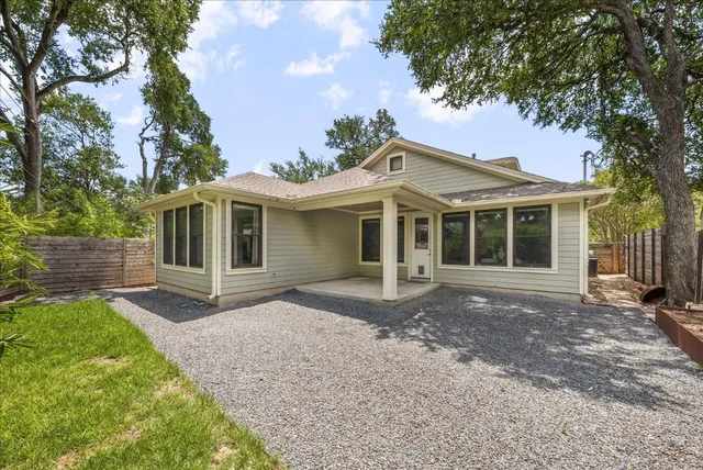 a view of a house with a yard and large tree