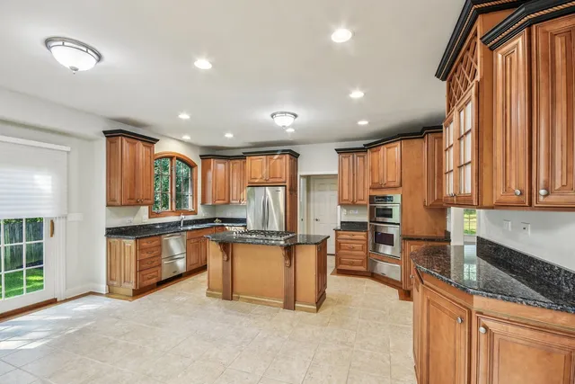 a kitchen with stainless steel appliances granite countertop a refrigerator a stove and a sink with wooden floor