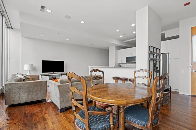 a living room with stainless steel appliances furniture a dining table and a flat screen tv