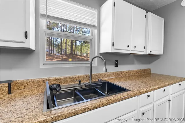 a kitchen with granite countertop a sink and white cabinets