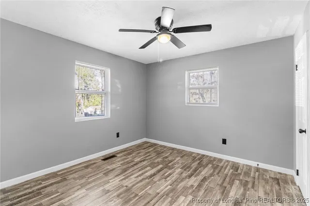 a view of empty room with window and ceiling fan