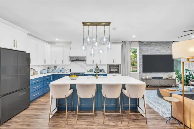 a kitchen with stainless steel appliances granite countertop a stove a sink dishwasher and white cabinets with wooden floor