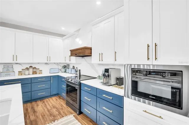 a kitchen with stainless steel appliances kitchen island granite countertop a refrigerator a sink dishwasher and a stove with wooden floor