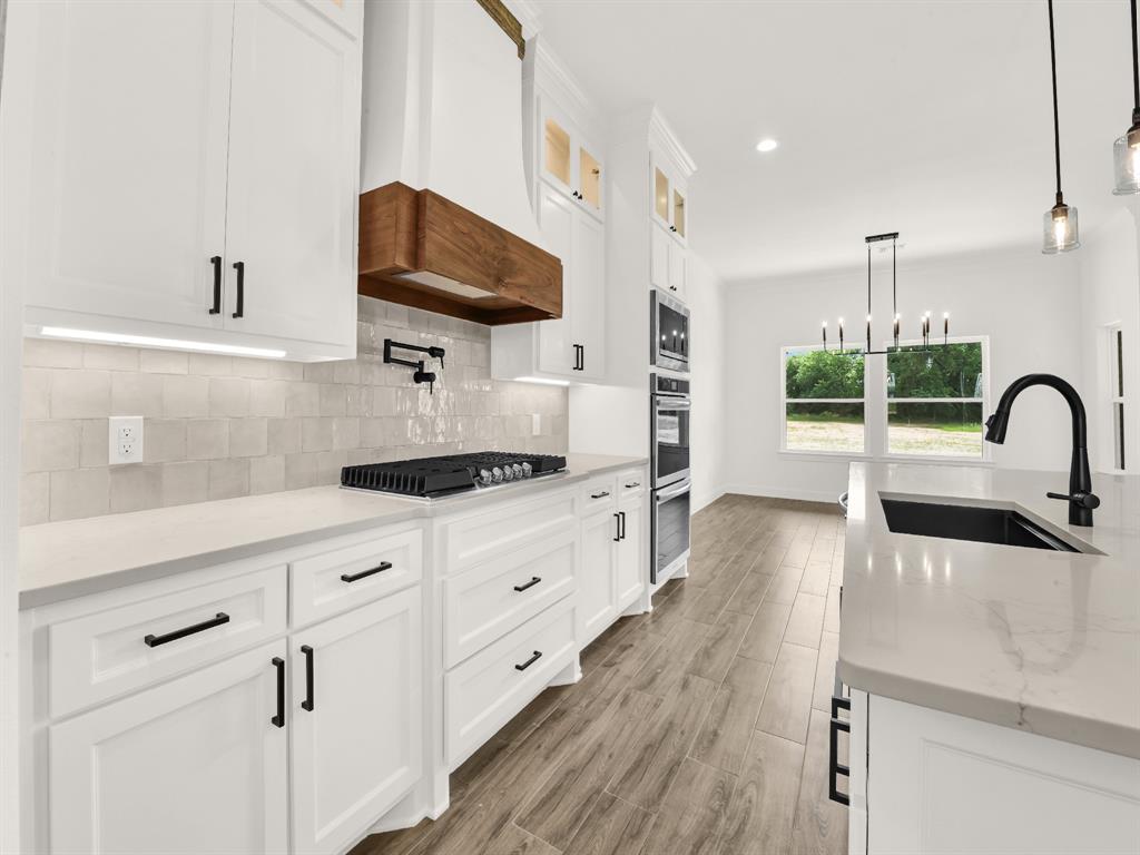 143 Desperado Way Weatherford, TX 76088 - Photo 11 of 36 Kitchen with a sink, appliances with stainless steel finishes, custom range hood, backsplash, and white cabinetry