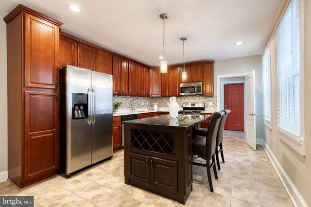 a kitchen with stainless steel appliances granite countertop a refrigerator a stove a sink a dining table and chairs with wooden floor